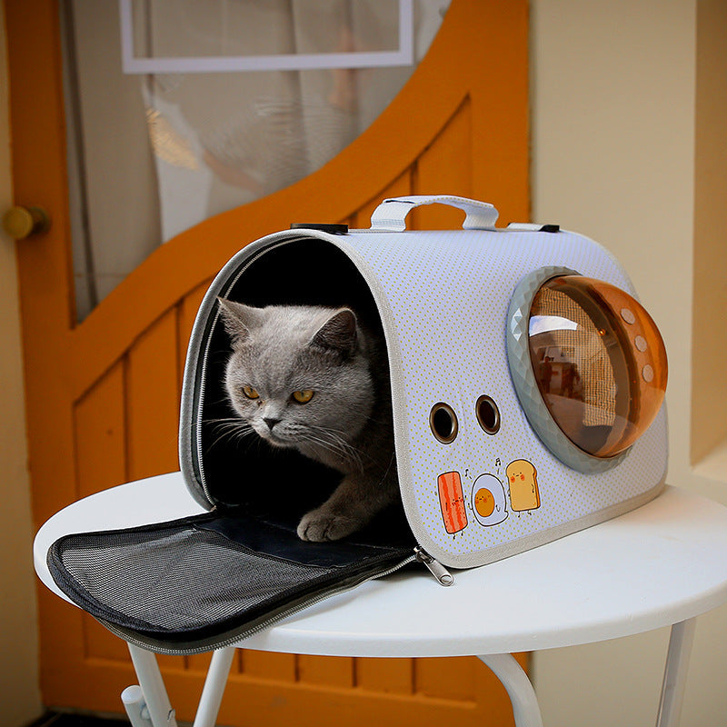 Cat peeking out from a pet carrier with a design resembling a robot on a white surface.