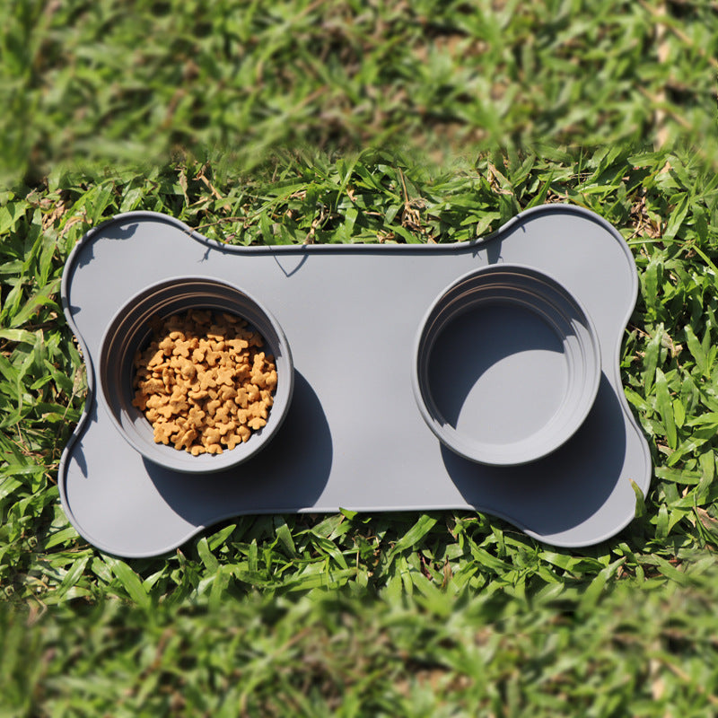 Gray bone-shaped pet feeder with two compartments on grass