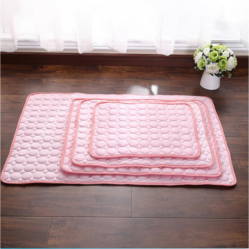 Set of pink quilted mats on a wooden floor with a vase of flowers in the background.