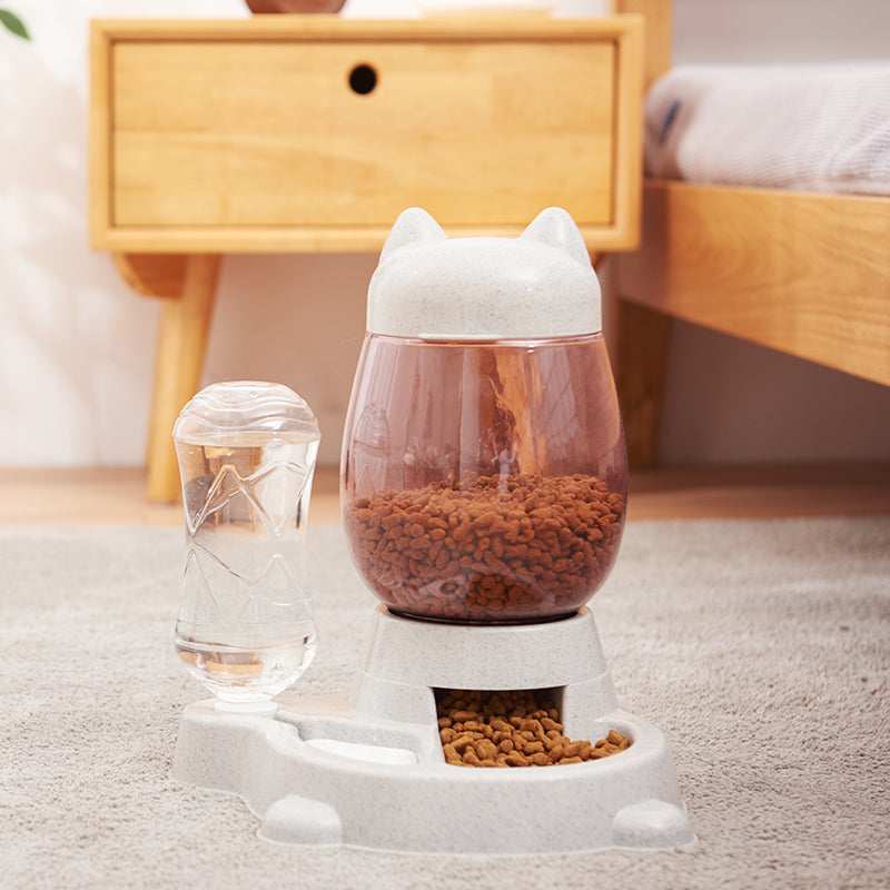 Pet food and water bowl with cat-shaped design on a carpeted floor.