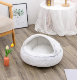 White pet bed on a wooden floor with a blurred background