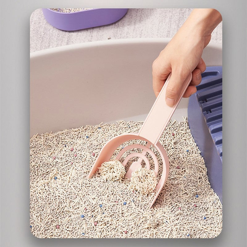 Person using a pink scoop to clean a cat litter box filled with clumping cat litter.