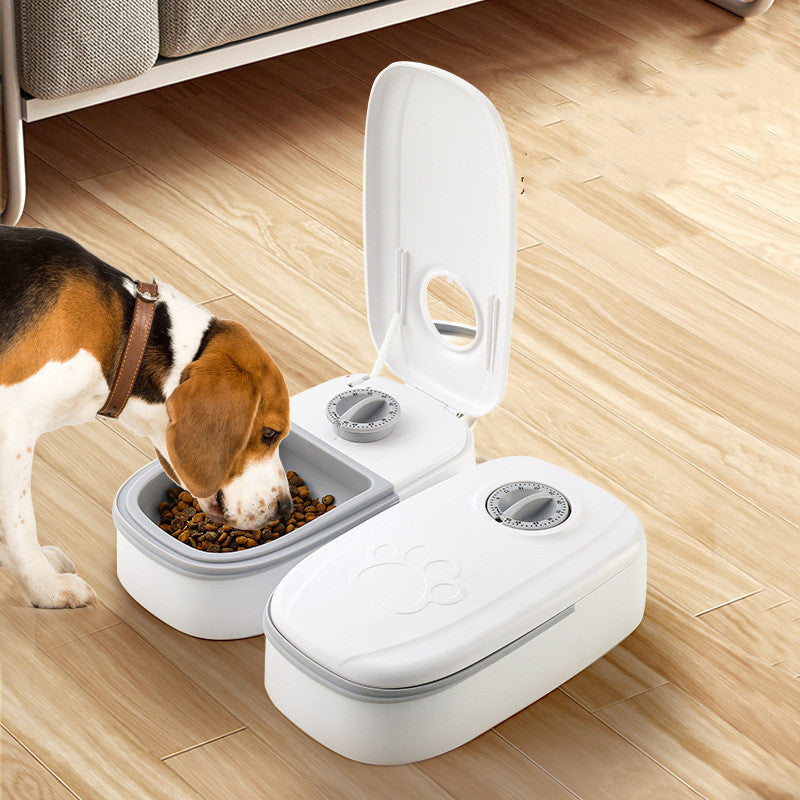 Dog eating from a white pet feeder on a wooden floor.